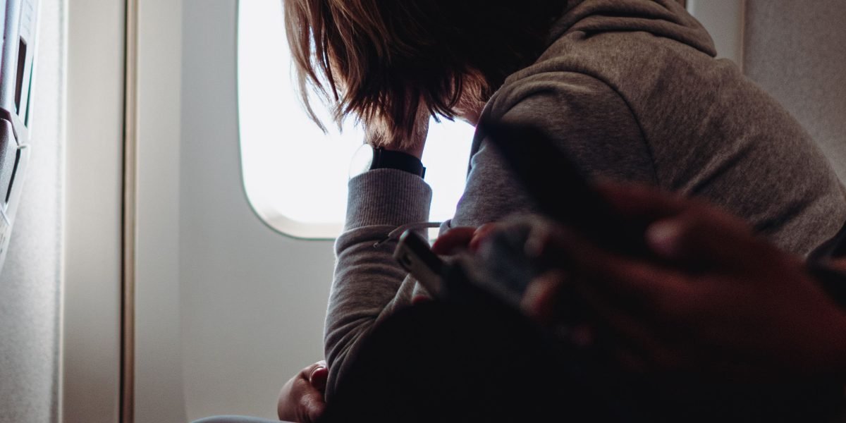 A person looking calmly out an airplane window, symbolizing overcoming aerophobia and enjoying travel.
