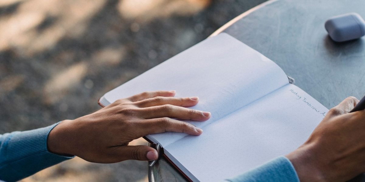 A person writing in a journal with a pen, reflecting on their thoughts and feelings, preparing for a therapy session.