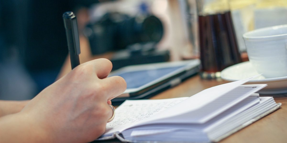 A person writing in a journal, reflecting on their thoughts and feelings, illustrating the practice of symptom tracking.